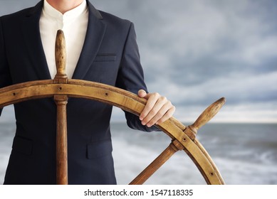 Businessman holding ship wheel and navigates in storm.