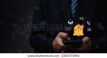 Businessman holding smart phone with virtual bell ringing for notification alert concept. social media and internet network, email, telephone, chat, shopping online.