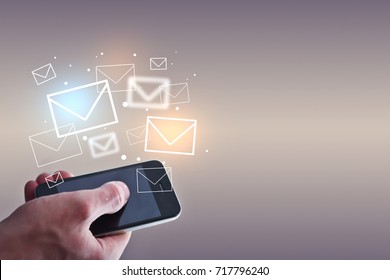 Businessman holding smartphone with emails on light background. Email marketing concept - Shutterstock ID 717796240