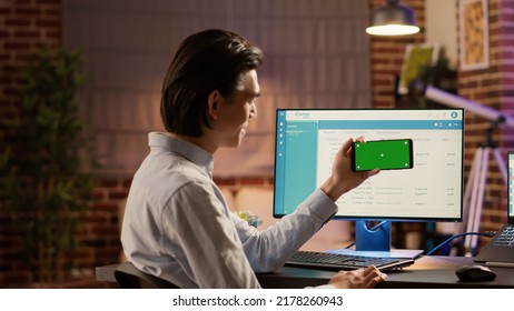 Businessman Holding Smartphone With Horizontal Greenscreen At Desk. Looking At Isolated Mockup Background With Blank Copyspace And Chroma Key Template On Mobile Phone Display. Web App