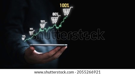 Businessman holding smartphone which display virtual graph chart and shopping trolley cart for  increasing of online sale business growth concept.