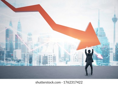 Businessman holding stock crash red arrow on city background. Business and financial crisis concept.