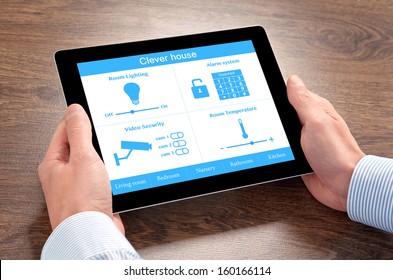 businessman holding a tablet computer with system clever house over the villages table - Powered by Shutterstock