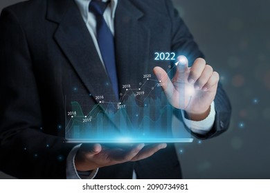  Businessman holding tablet with draws increase arrow graph corporate future growth year 2021 to 2022. Development to success and growth business concept.
