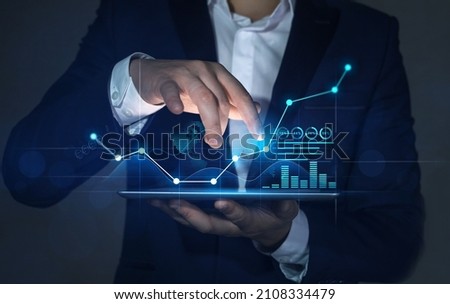 Businessman holding tablet with growing virtual hologram of statistics, graph and chart.Business strategy development and growing growth plan. Investment of growth on currency rate.