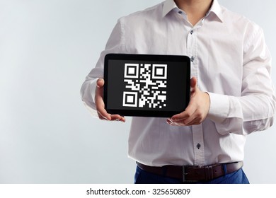 Businessman holding tablet PC with QR code on screen