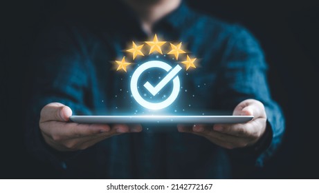 Businessman holding tablet and showing the best quality assurance with golden five stars for guarantee product and ISO service concept. - Shutterstock ID 2142772167