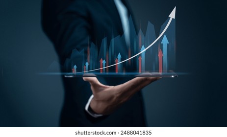 Businessman holding tablet and showing holographic graphs and stock market statistics gain profits. Concept of growth planning and business strategy. - Powered by Shutterstock