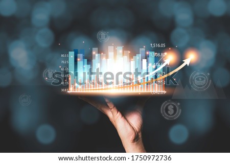 Businessman holding tablet with virtual statistic hologram graph and chart. Stock investor have to analysis profit and business data before investment.