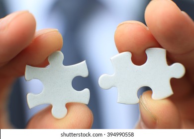 Businessman holding two blank white puzzle pieces in his hands conceptual of solving a problem, growth and development.
