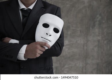Businessman holding white mask in his hand dishonest cheating agreement.Faking and betray business partnership concept