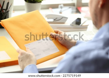 Businessman holding yellow package with mail in office