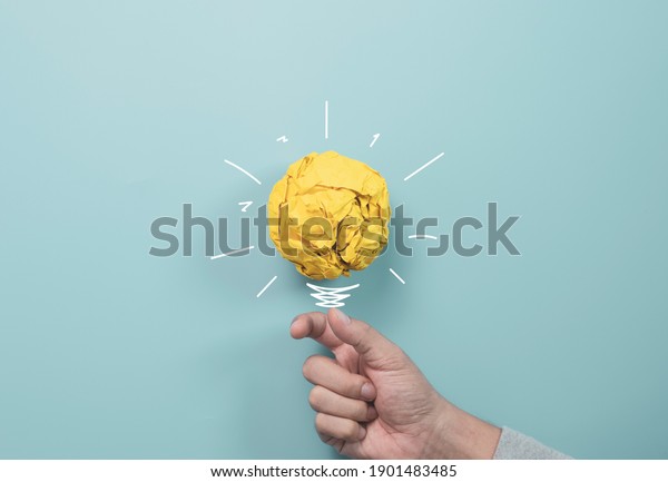 Businessman holding yellow scrap paper ball with\
illustration painting for virtual lightbulb. It is creative\
thinking idea and innovation\
concept.