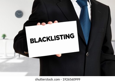 Businessman Holds A Card With The Word Blacklisting Written On It. Blacklist Unwanted People, Calls Or Messages.

