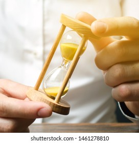 Businessman Holds Clock In Hands. Concept Of Saving Time And Money. Time Management. Planning Work. Reduced Cost And Bureaucratic Burden. Saving Productivity. Extension Of Life. Debt / Tax Holidays