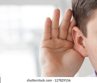 Businessman holds his hand near his ear and listening something - Shutterstock ID 127829156