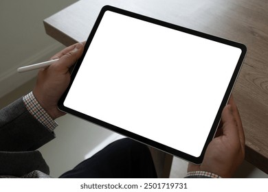 A businessman holds a mockup. iPad digital tablet with blank screen Mockup replaces your design mockup in the office.