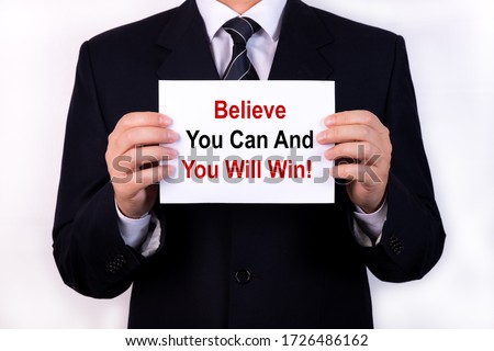 Businessman holds a tablet with the text BELIVE YOU CAN AND YOU WILL WIN. Business concept