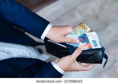 A businessman holds a wallet filled with Swiss francs in his hands. Swiss economy, finance and business