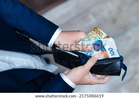 A businessman holds a wallet filled with Swiss francs in his hands. Swiss economy, finance and business