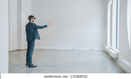 Businessman in Holographic Augmented Reality Glasses Standing in Empty Office and Map it. Sunlight Shines Through Big Windows. - Powered by Shutterstock