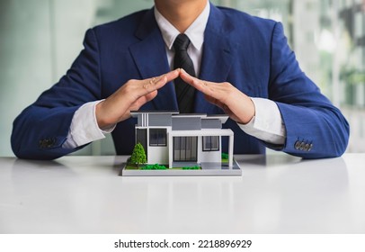 Businessman Or Home Insurance Broker Holding A Small Model House Offers Home Insurance. House Trading