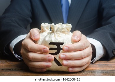 Businessman hugs indian rupee money bags. Granting financing business project or education. Trade, economics. Corruption. Provision financial loan credit. Bank deposit. Budget, tax collection. - Shutterstock ID 1642008415