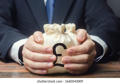 Businessman hugs pound sterling money bags. Budget, tax collection. Granting financing business project. Trade, economics. Growth of corruption kickbacks, appropriation of funds. Provision loan. - Shutterstock ID 1660543009