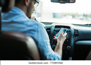 Businessman ignoring safety and texting on mobile phone while driving - Shutterstock ID 772891960