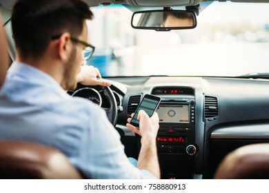 Businessman Ignoring Safety And Texting Onmobile Phone While Driving