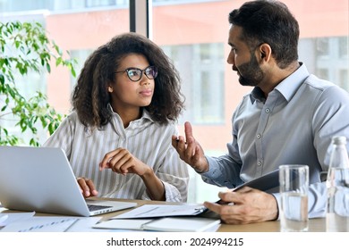 Businessman indian executive manager ceo talking to female African American coworker, using laptop. Diverse multicultural professional partners group discussing business plan at board room meeting. - Shutterstock ID 2024994215