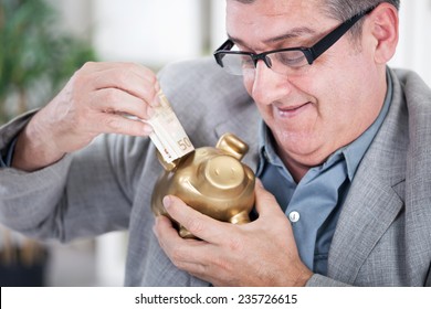  Businessman Inserting Money To A Piggy Ban