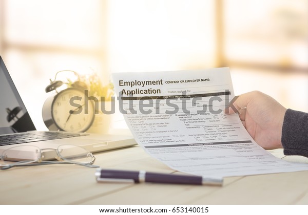 Businessman or job seeker\
fill in Employment Application form with pen to get a new job. job\
vacancy concept.