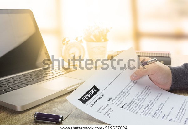 Businessman or job seeker review his resume on\
his desk before send to finding a new job with pen, necktie,\
glasses and digital\
tablet.