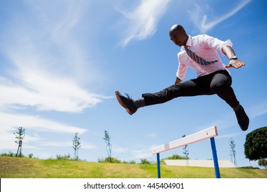 Businessman jumping a hurdle while running on the racing track - Powered by Shutterstock