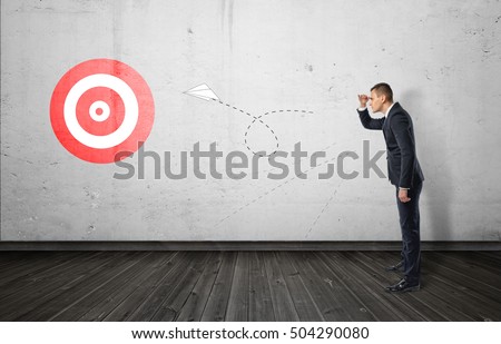 Businessman keeping track of the paper airplane flying right on target. Long-term plan. Distant goal. Total control. Stock fotó © 