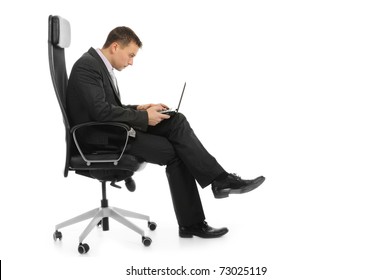 Businessman With A Laptop Sitting In A Chair In A Bright Office. Isolated On White Background