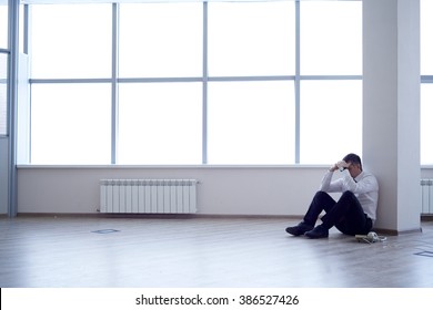 Businessman (lawyer, Insurance Agent, Supervisor, Manager) Is Sitting On The Floor In An Empty Office. Next To Him, Only The Phone. His Company Went Bankrupt/Business Went Bankrupt