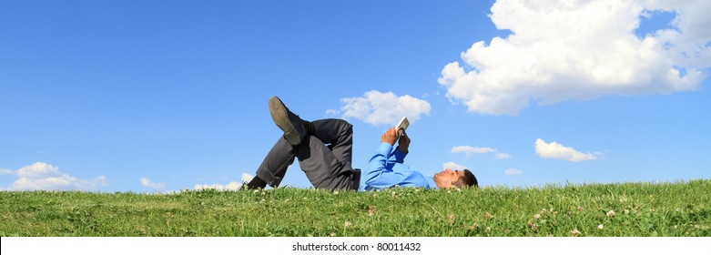 businessman laying down on the grass and working with tablet - Powered by Shutterstock