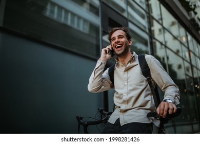 Businessman leaning on his bike against office building and having phone call - Powered by Shutterstock