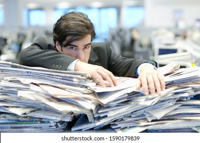 Businessman Leaning On Pile Of Paperwork