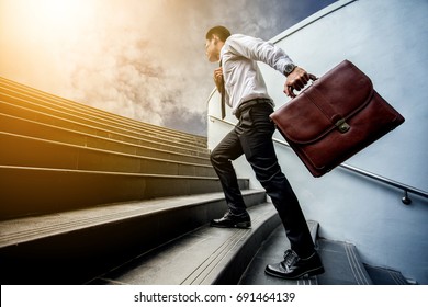 Businessman leap up the stairs to the light.He is boldly and active.. his hand hold a brown leather briefcase.