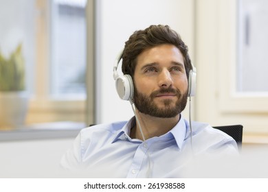 Businessman Listening Music  In Headphones. Modern Office