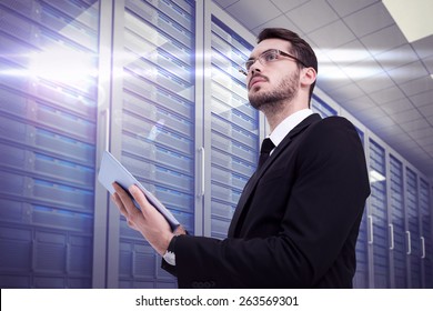 Businessman looking away while using tablet against server room