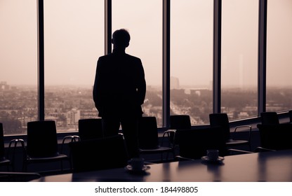 Businessman Looking At City Through Window, Before Boardroom Meeting