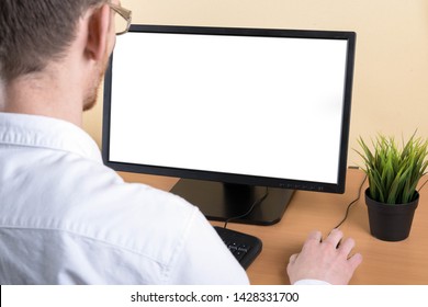 
Businessman Looking At Computer Screen Using A Desktop Computer With A View Over His Shoulder From Behind Of The Blank Screen Of The Monitor With Copy Space,text