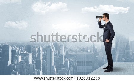 Businessman looking forward to a city  with binoculars from skyscraper concept
