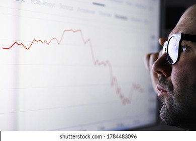 A businessman is looking at a graph on a monitor. An exchange broker evaluates stock market trends. A man with glasses in front of a curve of the dynamics of economy.