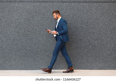 Businessman Looking At His Mobile Phone While Walking On Street To Office.