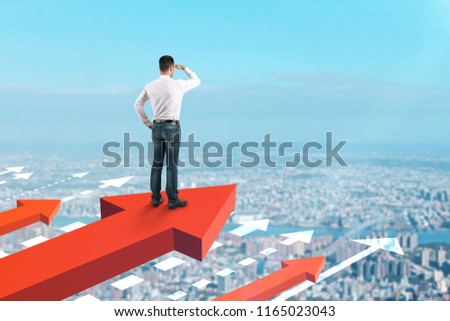Businessman looking into the distance on red arrows. Blue sky background. Growth and development concept 